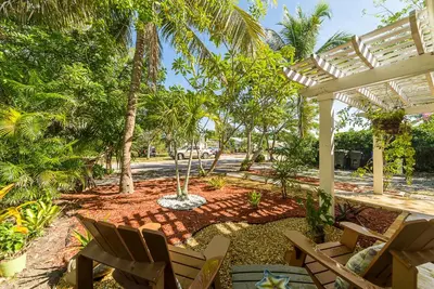 a patio with chairs and a pergola and palm trees at The Blue Door Inn in Fort Lauderdale