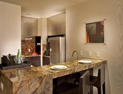 a kitchen with a counter with chairs and a refrigerator at EB Hotel Miami Airport in Miami