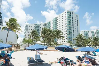 a group of people sitting on a beach with blue umbrellas at Miami Hollywood Great 2 Bedroom 2 Bathroom with Intercostal View 001-22bvic in Hollywood