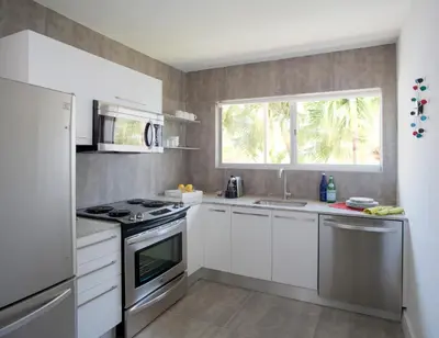 a kitchen with white cabinets and a sink and a window at 1818 Meridian House Apartments and Suites by Eskape Collection in Miami Beach