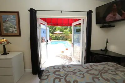 a bedroom with a door open to a swimming pool at Fantasy Island Inn, Caters to Men in Fort Lauderdale