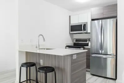 a kitchen with a stainless steel refrigerator and two bar stools at Amazing 2 BR Condo At Wynwood With Parking in Miami