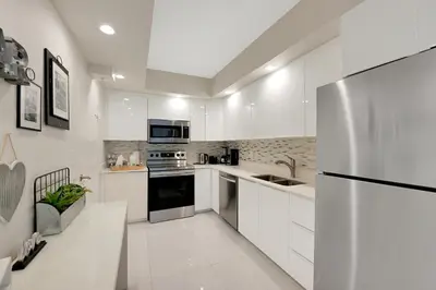 a kitchen with white cabinets and a stainless steel refrigerator at The Tides Apartments on the beach in Hollywood