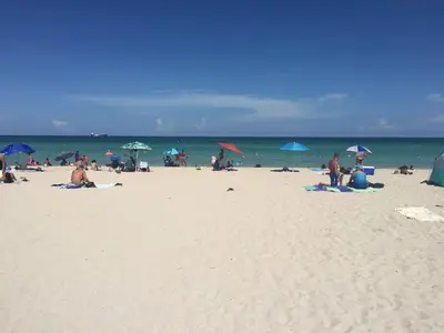 a group of people on a beach with umbrellas at Heart of South Beach / Modern Apartment / Ocean Drive - Carlyle in Miami Beach