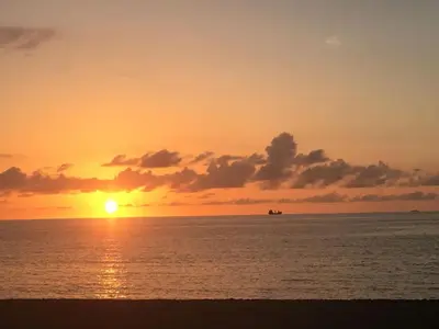a sunset on the beach with a boat in the ocean at Heart of South Beach / Modern Apartment / Ocean Drive - Carlyle in Miami Beach