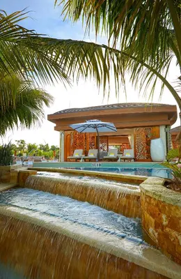 a resort with a waterfall and a pool with an umbrella at The Guitar Hotel at Seminole Hard Rock Hotel & Casino in Fort Lauderdale
