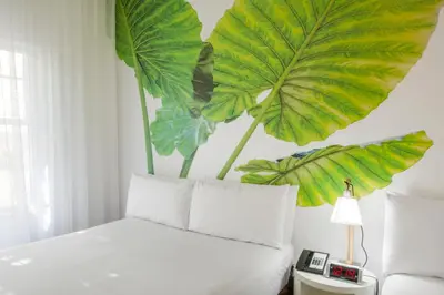 a bedroom with a bed with large leaves on the wall at President Hotel in Miami Beach