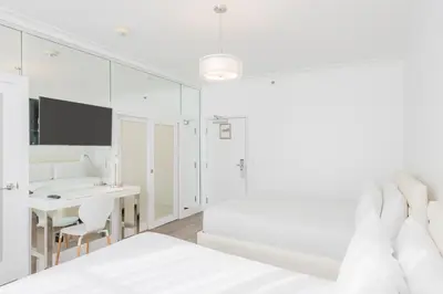 a white bedroom with a desk and a bed at President Hotel in Miami Beach