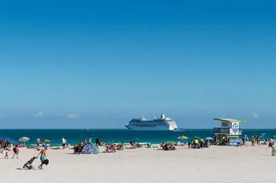 a group of people on a beach with a cruise ship at President Hotel in Miami Beach