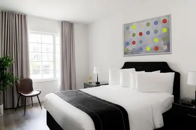 a bedroom with a large white bed and a chair at Essex House Hotel in Miami Beach