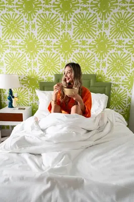 a woman sitting in bed eating a plate at Circa 39 Miami Beach in Miami Beach