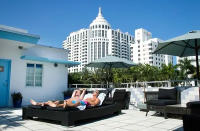 two people laying on a couch in front of a building at Aqua Hotel & Suites in Miami Beach