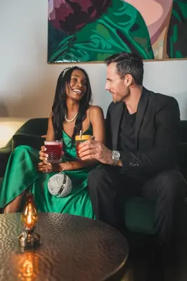 a man and a woman sitting on a couch with drinks at National Hotel, An Adult Only Oceanfront Resort in Miami Beach