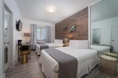 a hotel room with two beds and a television at Century Hotel in Miami Beach