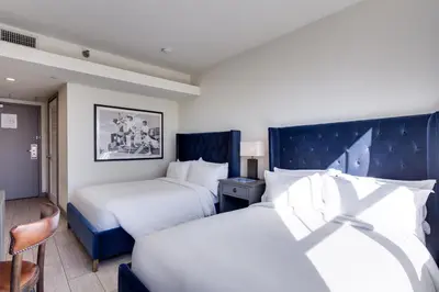 a hotel room with two beds and a chair at Clinton Hotel South Beach in Miami Beach