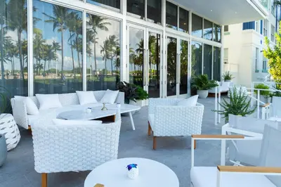 a patio with white chairs and tables and windows at Park Central South Beach in Miami Beach