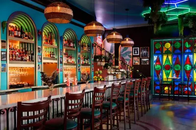 a bar with a row of chairs in a room with stained glass windows at Park Central South Beach in Miami Beach