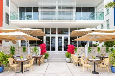 a patio with tables and umbrellas in front of a building at Park Central South Beach in Miami Beach