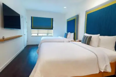a hotel room with two beds and a television at The Tony Hotel South Beach in Miami Beach