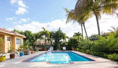 a swimming pool in a yard with palm trees at Yuli's Home in Miami