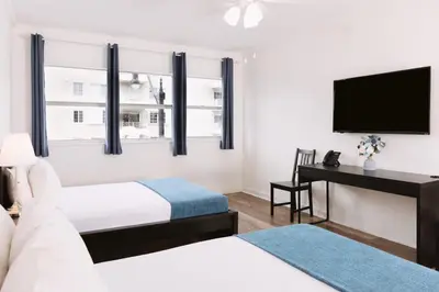a hotel room with two beds and a desk and a television at Lorraine Hotel in Miami Beach