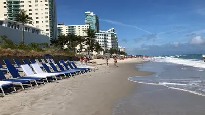 a beach with chairs and the ocean and buildings at Hide House in Hollywood