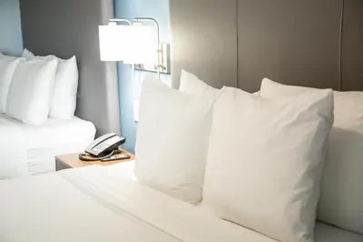 a hotel room with a bed with pillows and a phone at Regency Miami Airport by Sonesta in Miami