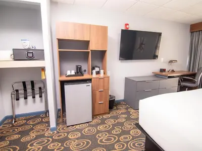 a room with a kitchen with a desk and a tv at Regency Miami Airport by Sonesta in Miami