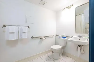a white bathroom with a toilet and a sink at Regency Miami Airport by Sonesta in Miami