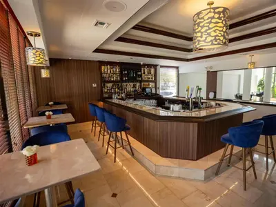 a bar in a restaurant with blue chairs and tables at Regency Miami Airport by Sonesta in Miami