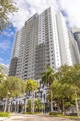 a large white building with palm trees in front of it at Fortune House Hotel Suites in Miami