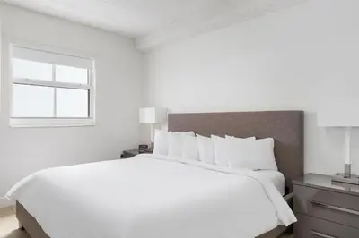 a white bedroom with a large bed and a window at Fortune House Hotel Suites in Miami