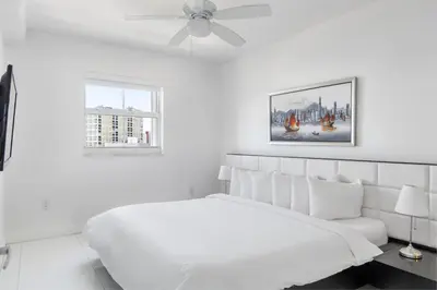 a white bedroom with a white bed and a ceiling fan at Fortune House Hotel Suites in Miami