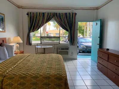 a bedroom with a bed and a table and a window at International Inn on the Bay in Miami Beach