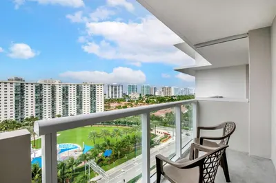 a balcony with two chairs and a view of a city at Ramada Plaza by Wyndham Marco Polo Beach Resort in Miami Beach
