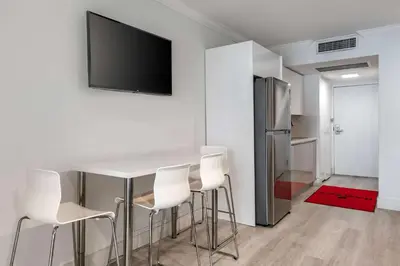 a kitchen with a table with chairs and a television on a wall at Ramada Plaza by Wyndham Marco Polo Beach Resort in Miami Beach