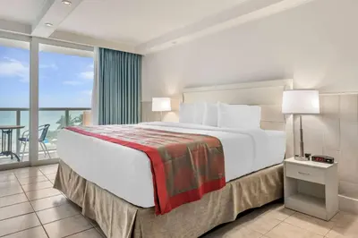 a hotel room with a large bed and a balcony at Ramada Plaza by Wyndham Marco Polo Beach Resort in Miami Beach