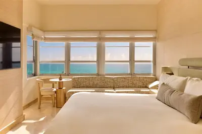 a bedroom with a bed and a couch and a window at The Shelborne by Proper, a Member of Design Hotels in Miami Beach