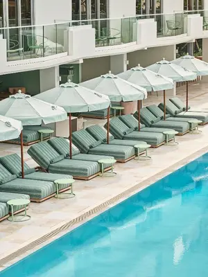 a row of lounge chairs with umbrellas next to a swimming pool at The Shelborne by Proper, a Member of Design Hotels in Miami Beach