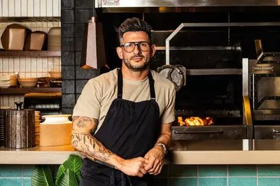 a man wearing glasses and an apron standing in a kitchen at Mayfair House Hotel & Garden in Miami