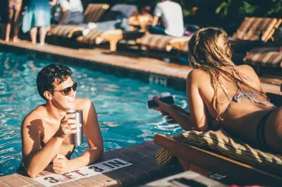 a man and a woman sitting in a swimming pool at Freehand Miami in Miami Beach