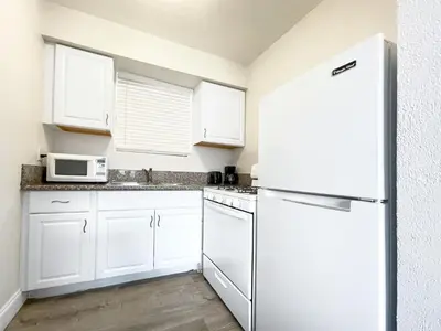 a kitchen with white cabinets and a white refrigerator at Greniers in Hollywood