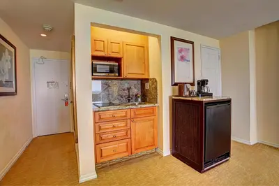 a kitchen with wooden cabinets and a sink and a refrigerator at Sea View Hotel in Miami Beach