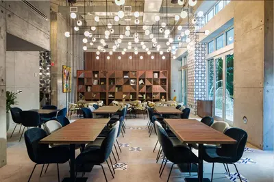 a restaurant with wooden tables and chairs and chandeliers at Hotel Indigo Miami Brickell by IHG in Miami