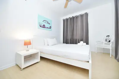 a white bedroom with a white bed and a chair at Sobe Apartments in Miami Beach
