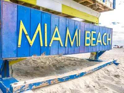 a blue beach bench with the miami beach sign on it at Sobe Apartments in Miami Beach