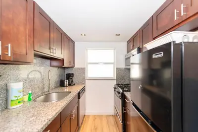 a kitchen with wooden cabinets and a stainless steel refrigerator at Sofi Beach Apartments in Miami Beach