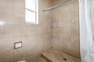 a bathroom with a shower with a toilet and a window at Ocean Beach Suites in Miami Beach