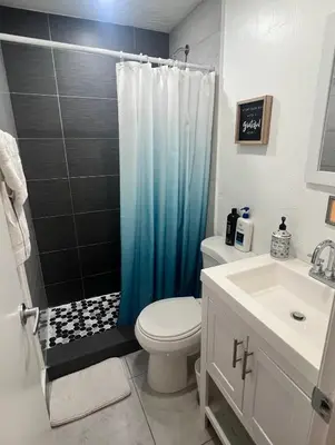 a bathroom with a toilet and a blue shower curtain at Miami Beach Rooms B&B in Miami Beach