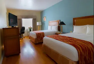 a hotel room with two beds and a flat screen tv at Rodeway Inn South Miami - Coral Gables in Miami